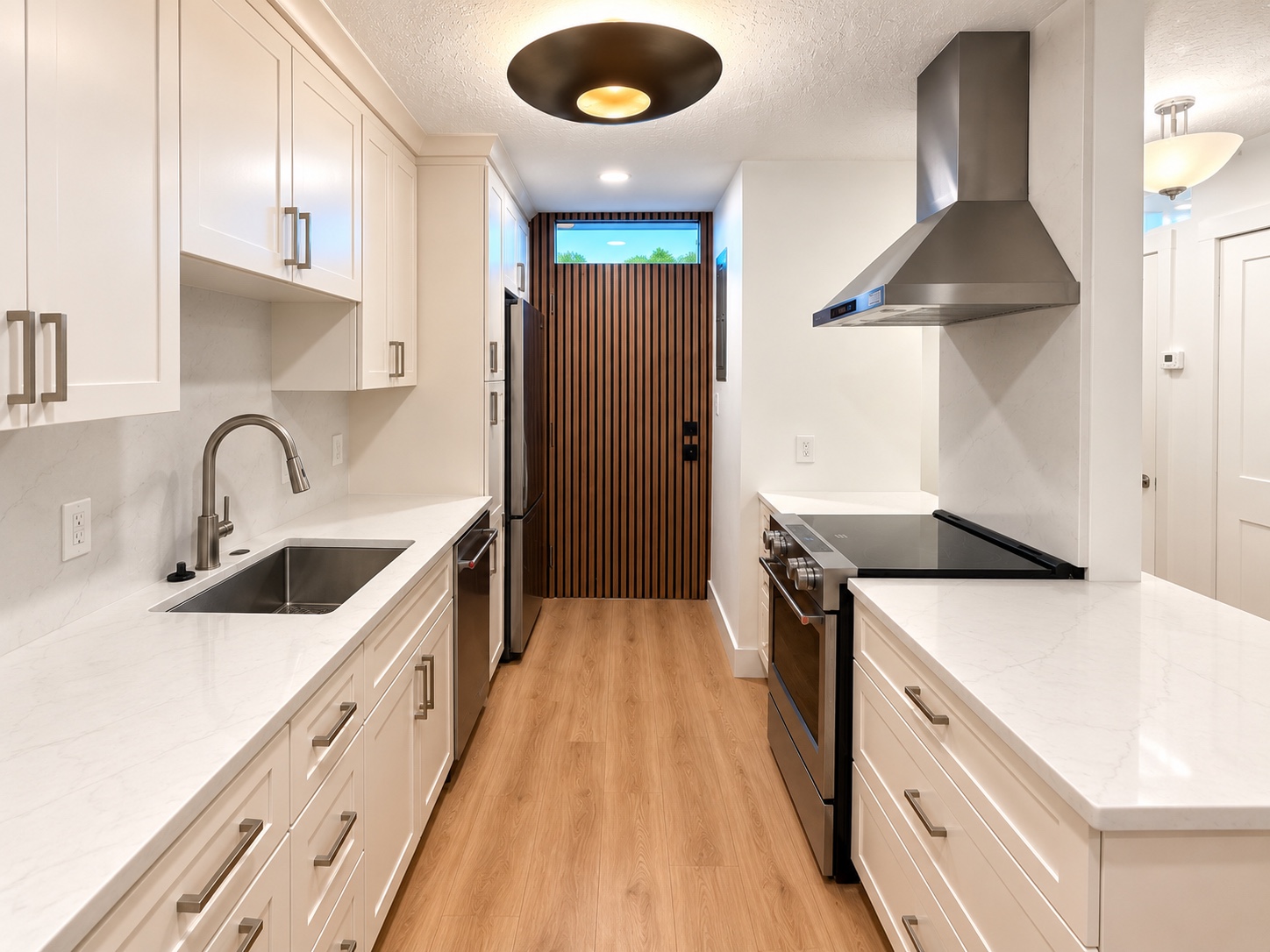 Finished kitchen with white counters and cabinetry, stainless range hood and wood-paneled door